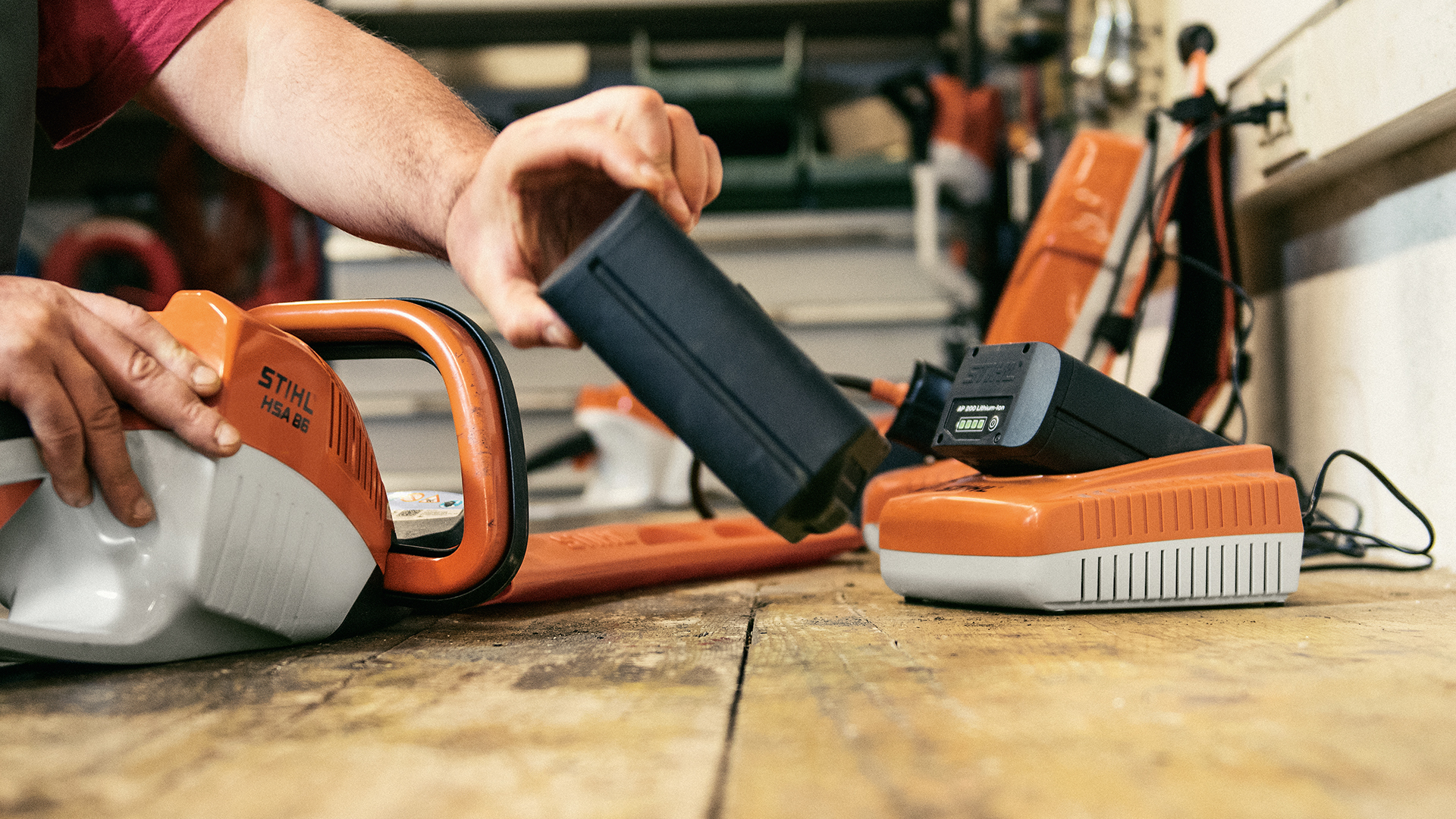 Un homme utilise la batterie STIHL AP et le chargeur rapide STIHL AL 300 avec un taille-haie sur batterie STIHL HSA 86